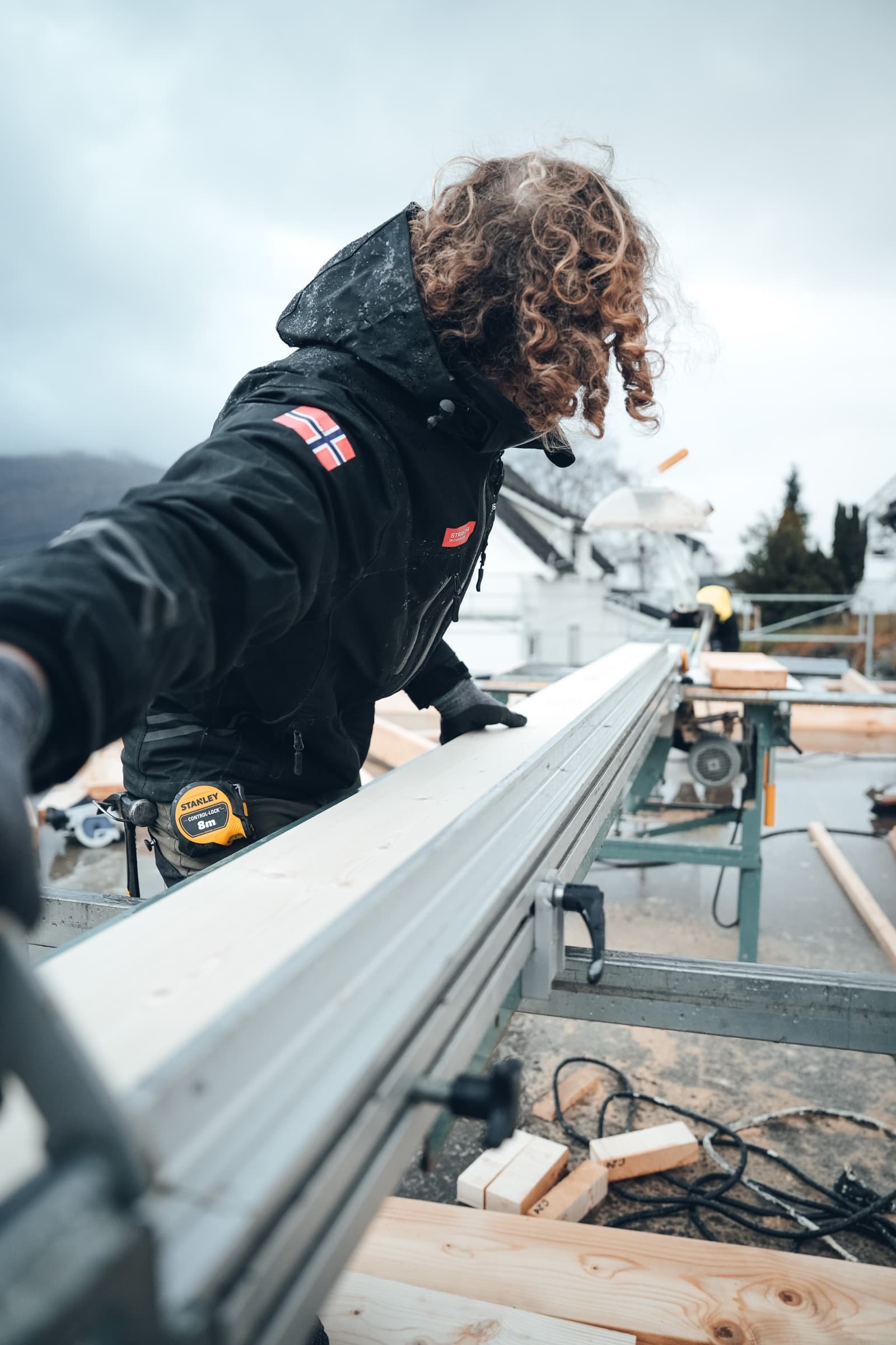 Tømrer måler opp materialer på kappsagen